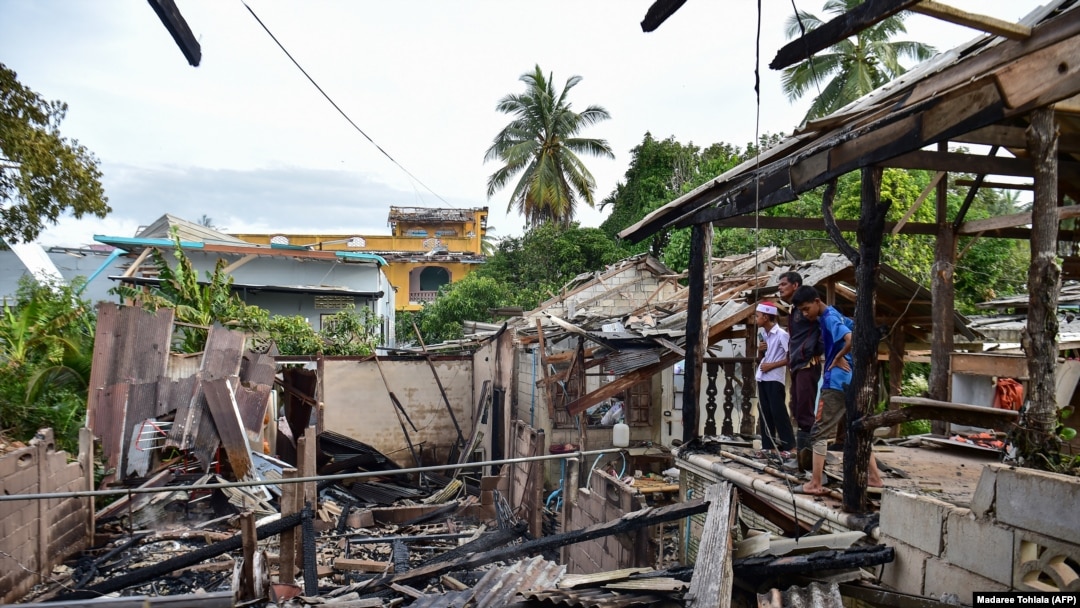 Warga memperhatikan puing-puing rumah yang hancur akibat ledakan di pabrik kembang api di Sungai Kolok, Provinsi Narathiwat, Thailand, Sabtu, 29 Juli 2023. Sembilan orang tewas dalam ledakan itu.(Foto: Madaree Tohlala/AFP)