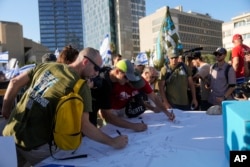 Israeli military reservists sign a declaration of refusal to report for duty to protest against plans by Prime Minister Benjamin Netanyahu's government to overhaul the judicial system, in Tel Aviv, Israel, July 19, 2023.