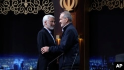 In this photo made available by Iranian state-run TV, IRIB, Iranian presidential candidates Saeed Jalili, left, and Masoud Pezeshkian greet one another at the conclusion of a debate in Tehran, Iran, June 1, 2024. (Morteza Fakhri Nezhad/IRIB via AP)