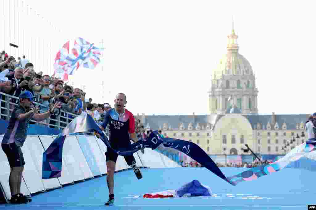 France&#39;s Jules Ribstein celebrates as he crosses the finish line to win the men&#39;s PTS2 para triathlon event at the Paris 2024 Paralympic Games at the Pont Alexandre III.