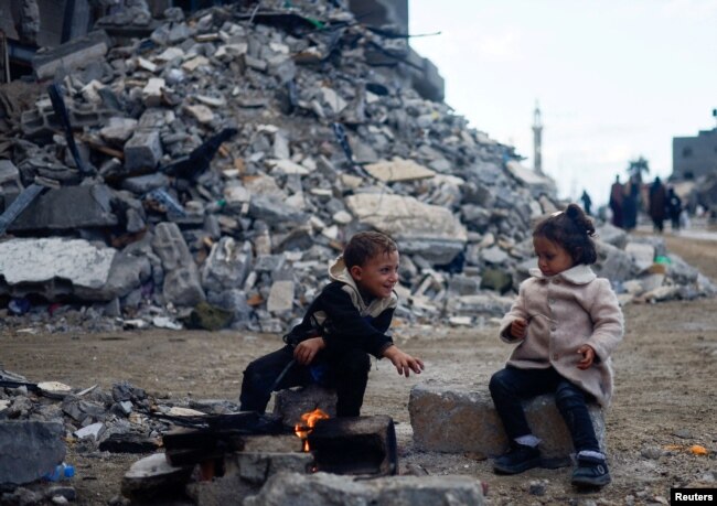 Palestinian children sit by the fire next to the rubble of a house hit in an Israeli strike during the conflict, amid a temporary truce between Hamas and Israel, in Khan Younis in the southern Gaza Strip, Nov. 27, 2023.