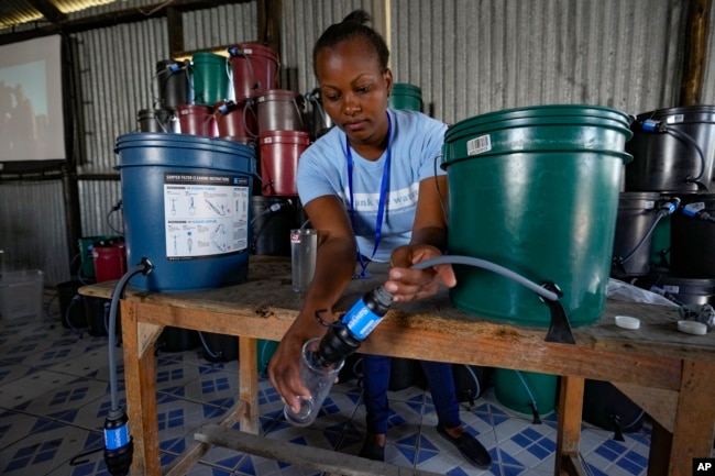 Hellen Simichi, a member of the Bucket Ministry, a Christian nonprofit organization, demonstrates how to use a bucket filter to locals in Athi River, Machakos county, Kenya, Oct. 17, 2023.