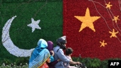 A family rides past a decoration in the shape of the national flags of China and Pakistan installed along a road ahead of a visit by Chinese Vice Premier He Lifeng, in Lahore, Pakistan, July 30, 2023.