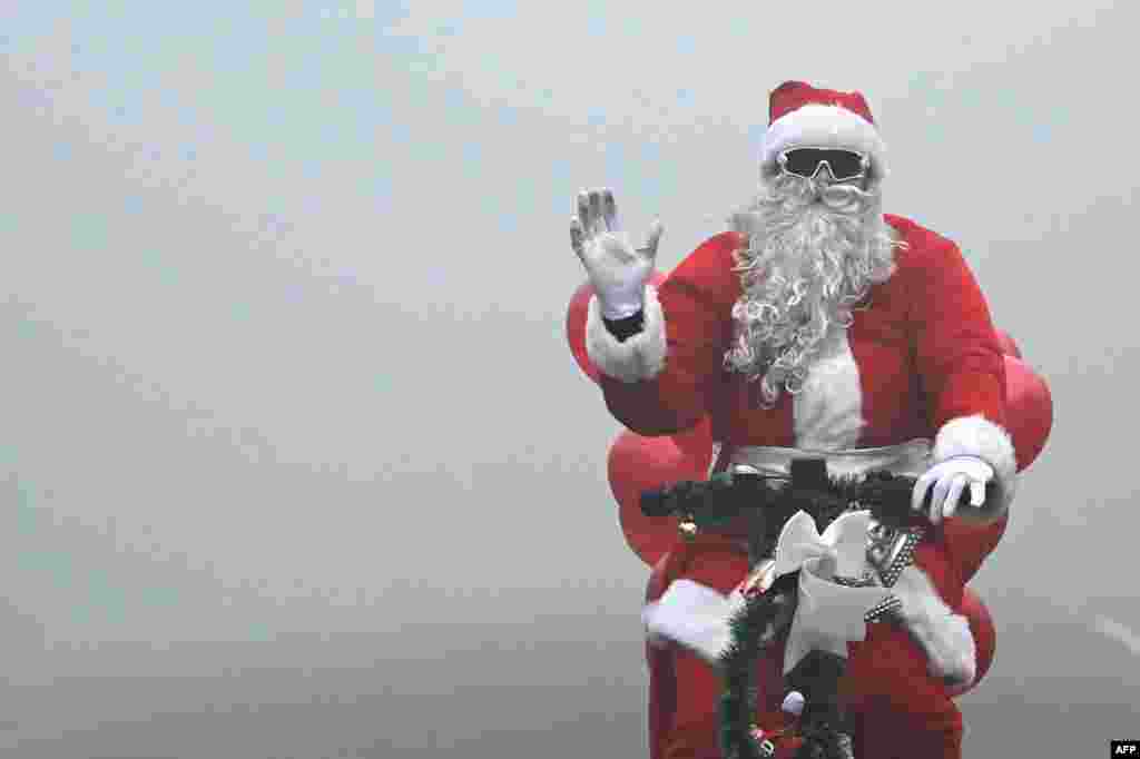 Santa Claus rides a cycle along a street engulfed in fog on Christmas in New Delhi on December 25, 2023.