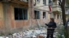 A woman stands near her apartment building damaged in a night attack in the town of Selydove, Donetsk region, on April 14, 2024.