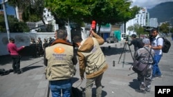 Journalists work in front of the Mexican embassy guarded by police in Quito on Apr. 7, 2024. 
