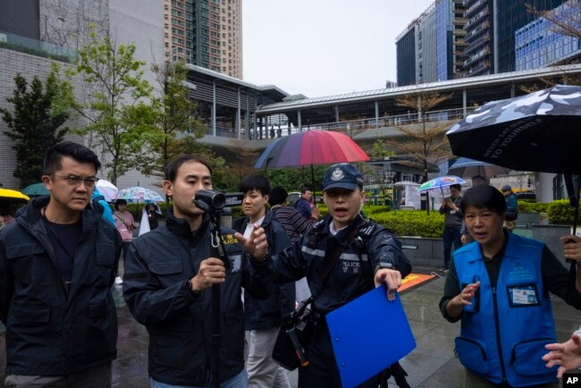 Police record member of the press during a rally in Hong Kong, March 26, 2023.