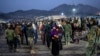 FILE - Taliban fighters stand guard as Afghan refugees wait to register in a camp near the Torkham Pakistan-Afghanistan border in Torkham, Afghanistan, Nov. 4, 2023. 