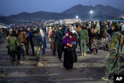 Taliban fighters stand guard as Afghan refugees wait to register in a camp near the Torkham Pakistan-Afghanistan border in Torkham, Afghanistan, Nov. 4, 2023. 