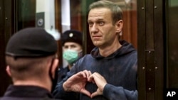 FILE - Pemimpin oposisi Rusia Alexey Navalny menunjukkan simbol hati dengan jari-jari tangannya, saat berdiri di dalam kurungan selama sidang di Pengadilan Kota Moskow, Rusia, 2 Februari 2021. Navalny meninggal dunia di penjara, pada usia 47 tahun. (Pengadilan Kota Moskow via AP)