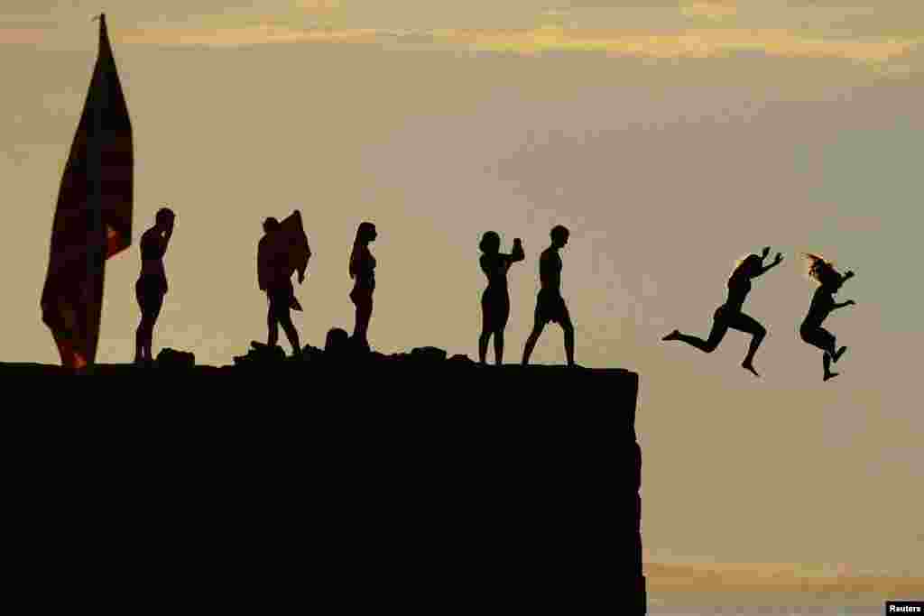 Kids jump off the breakwater into the ocean ahead the Fourth of July holiday in Gloucester, Massachusetts, July 3, 2023.