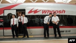 Staf China berdiri di samping kereta cepat Jakarta-Bandung 'Whoosh' seusai peresmian di stasiun Halim, Jakarta, 2 Oktober 2023. (Yasuyoshi CHIBA/AFP)