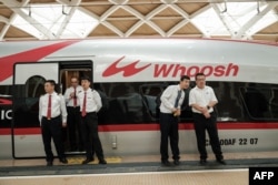 Staf China berdiri di samping kereta cepat Jakarta-Bandung 'Whoosh' usai peresmian di stasiun Halim, Jakarta, 2 Oktober 2023. (Yasuyoshi CHIBA / AFP)