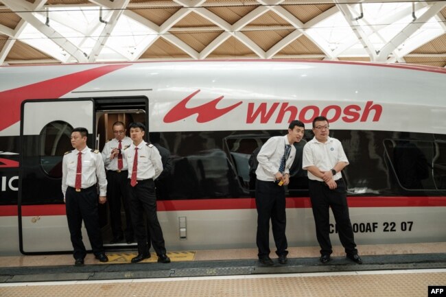 Staf China berdiri di samping kereta cepat Jakarta-Bandung 'Whoosh' usai peresmian di stasiun Halim, Jakarta, 2 Oktober 2023. (Yasuyoshi CHIBA / AFP)