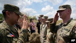 El Comandante del Regimiento de Artillería del Ejército de Filipinas, Anthony Coronel (izquierda), devuelve el saludo de un soldado estadounidense durante un simulacro militar conjunto en Laur, provincia de Nueva Ecija, norte de Filipinas, el viernes 31 de marzo de 2023.