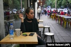 A woman sits at a cafe without her mandatory Islamic headscarf in Tehran, Iran, Saturday, April 29, 2023. (AP Photo/Vahid Salemi)