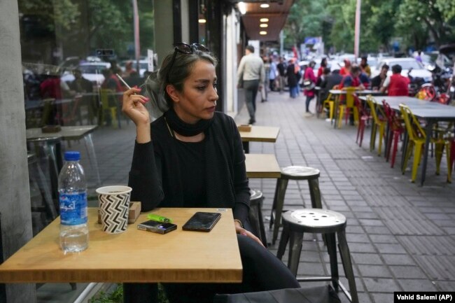 A woman sits at a cafe without her mandatory Islamic headscarf in Tehran, Iran, Saturday, April 29, 2023. (AP Photo/Vahid Salemi)