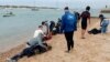 FILE - Para migran diselamatkan oleh penduduk setempat di tepi pantai, dekat kota barat daya Cádiz, Spanyol, 30 November 2023. (AP/Jorge Gonzalez Casares)