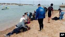 FILE - Para migran diselamatkan oleh penduduk setempat di tepi pantai, dekat kota barat daya Cádiz, Spanyol, 30 November 2023. (AP/Jorge Gonzalez Casares)