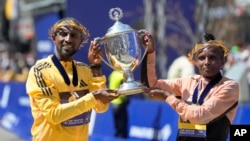 Sisay Lemma, of Ethiopia, left, winner of the men's division of the Boston Marathon, and Hellen Obiri, of Kenya, winner of the women's division of the race, hold the trophy on the finish line of the Boston Marathon in Boston, April 15, 2024.