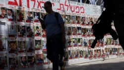 A man walks next to a silhouetted Israeli soldier holding a rifle and posters of hostages kidnapped during the deadly October 7 attack by Palestinian Islamist group Hamas from Gaza, at Dizengoff Square, in Tel Aviv, Israel, May 5, 2024. 