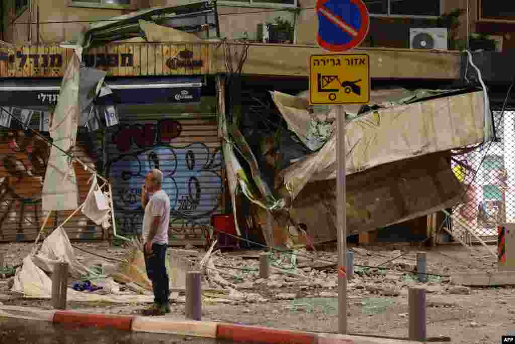 A man stands in front of a damaged shop in Tel Aviv, after it was hit by a rocket fired by Palestinian militants from the Gaza Strip, Oct. 7, 2023.