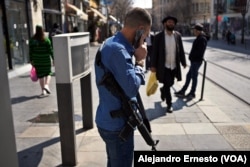 Un hombre armado con un fusil M16 espera el tranvía en la céntrica calle Jaffa, en Jerusalén.