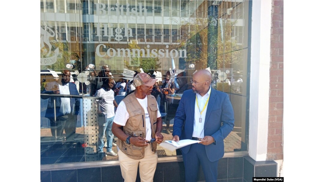 One of the march organizers, Poniso Shamukuni (left) hands over the petition to British High Commission's Mark Ssemakula in Gaborone, Botswana, March 12, 2024.