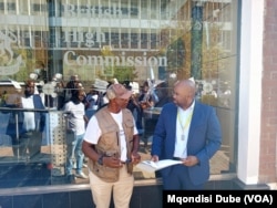 One of the march organizers, Poniso Shamukuni (left) hands over the petition to British High Commission's Mark Ssemakula in Gaborone, Botswana, March 12, 2024.