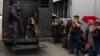 FILE - A truck with detainees passes by relatives of people detained during protests in Venezuela over the country's contested presidential election outside a police headquarters, in Caracas, Venezuela, Aug. 1, 2024. 