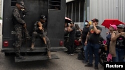 FILE - A truck with detainees passes by relatives of people detained during protests in Venezuela over the country's contested presidential election outside a police headquarters, in Caracas, Venezuela, Aug. 1, 2024. 