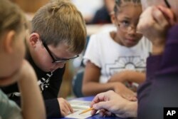 Dylan Mayes, left, reads from a book about Willie Mays during a reading circle in class on Thursday, Oct. 20, 2022, in Niagara Falls, N.Y. (AP Photo/Joshua Bessex)