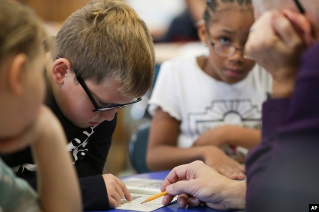 Dylan Mayes, left, reads from a book about Willie Mays during a reading circle in class on Thursday, Oct. 20, 2022, in Niagara Falls, N.Y. (AP Photo/Joshua Bessex)