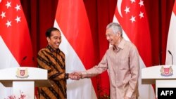 Perdana Menteri Singapura Lee Hsien Loong (kanan) dan Presiden Indonesia Joko Widodo (kiri) dalam konferensi pers bersama di Istana Singapura, 16 Maret 2023. (EDGAR SU/POOL/AFP)