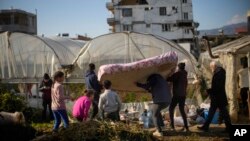 Local residents bring a mattress to a greenhouse where they shelter after the earthquake in Samandag, southern Turkey, Feb. 16, 2023