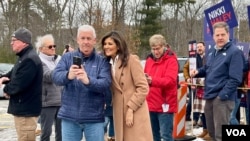 Former U.N. Ambassador Nikki Haley on primary day, taking a photo with a volunteer, Jan. 24, 2024. At right is New Hampshire Governor Chris Sununu, who has endorsed Haley. (Carolyn Presutti/VOA)