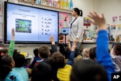 Christine Ramroop, who graduated from Bowie State University in 2020, teaches first graders during their warm-up for the day at Whitehall Elementary School, Tuesday, Jan. 24, 2023, in Bowie, Md.