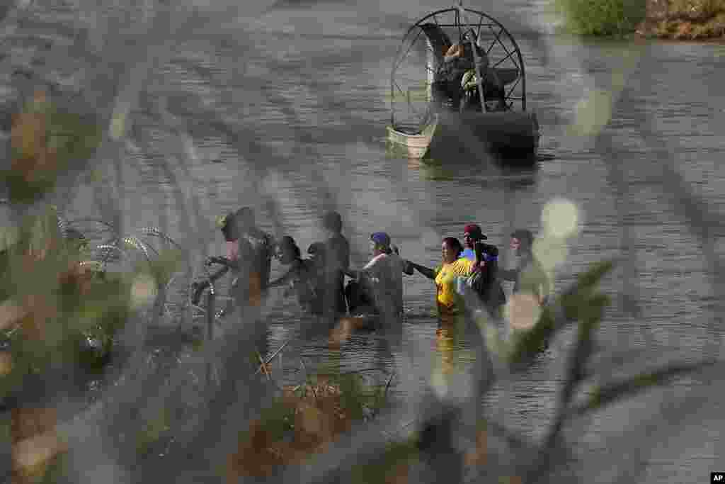 U.S. Border Patrol agents watch as migrants cross the Rio Grande from Mexico into the U.S., in Eagle Pass, Texas.