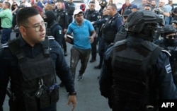 Policías desalojan a migrantes de un campamento instalado frente al Instituto Nacional de Migración (INM) en Ciudad Juárez, estado de Chihuahua, México, el 22 de mayo de 2023. [Foto: AFP]