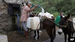 Emilia Segura fills containers with water at a public well in Pueblo Santa Cruz Acalpixca, Xochimilco, on the outskirts of Mexico City, Oct. 7, 2023.