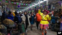 Seorang pedagang tampil mengenakan kostum di dekat penjual kentang dalam perayaan Hari Kentang Internasional di salah satu pasar di Lima, Peru, pada 30 Mei 2024. (Foto: AP/Martin Mejia)