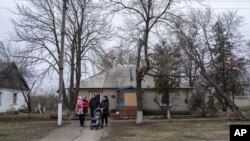 Una familia sale después de visitar a un voluntario médico de FRIDA Ucrania en la aldea de Khrestysche, región de Donetsk, Ucrania, el domingo 19 de marzo de 2023.