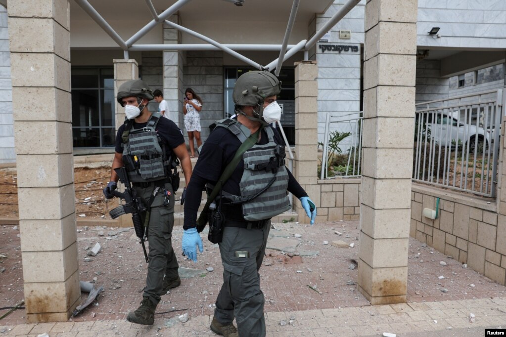 Miembros de los equipos de seguridad de Israel inspeccionan uno de los lugares impactados por misiles, en Ashkelon, sur de Israel.