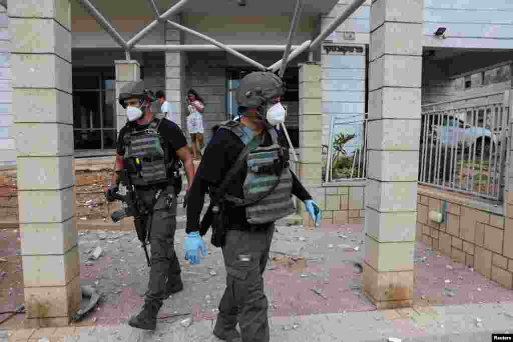 Miembros de los equipos de seguridad de Israel inspeccionan uno de los lugares impactados por misiles, en Ashkelon, sur de Israel.