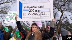 Abortion-rights activists holds signs as they protest outside of the U.S. Supreme Court during a rally in Washington, March 26, 2024.