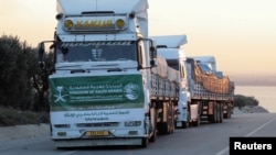 Aid trucks from Saudi Arabia line up at the border crossing from Turkey to Syria in the aftermath of an earthquake, Feb. 11, 2023.