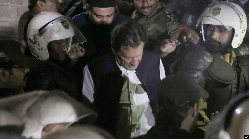 Police officers make way for former prime minister Imran Khan, center, upon his arrival at court, in Lahore, Pakistan, March 17, 2023. 