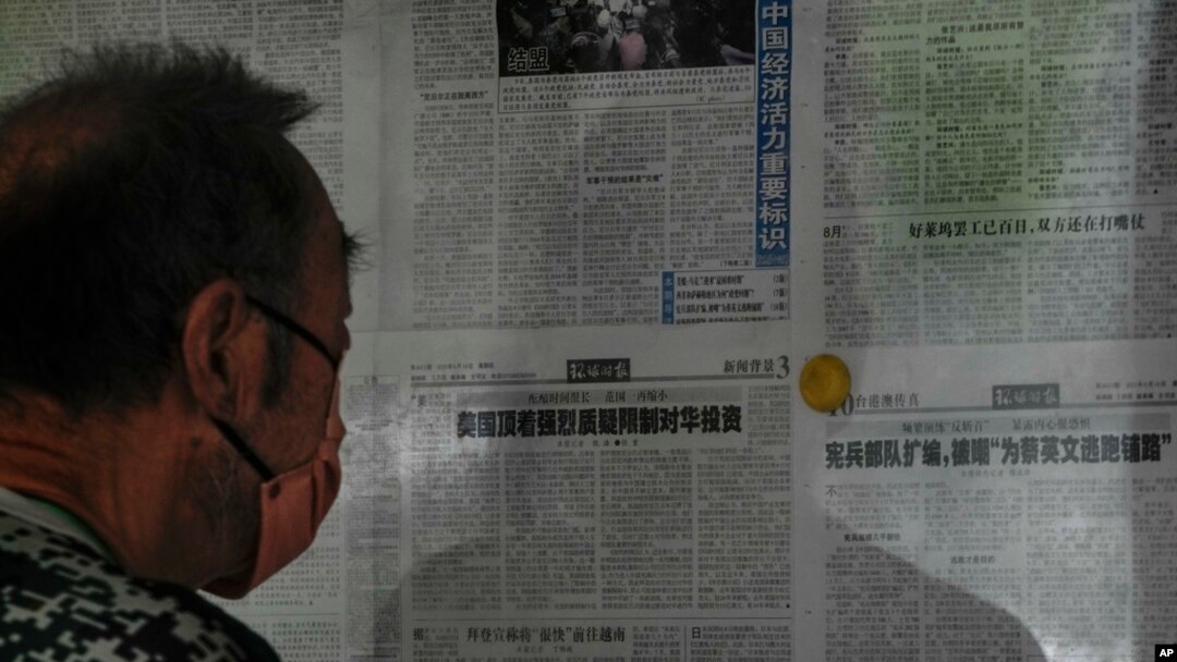 FILE - A man reads a Global Times article on investment curbs aimed at China, in Beijing, Aug. 10, 2023. China has accused Washington of trying to block its development via investment restrictions.