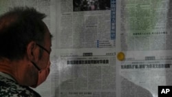 FILE - A man reads a Global Times article on investment curbs aimed at China, in Beijing, Aug. 10, 2023. China has accused Washington of trying to block its development via investment restrictions.