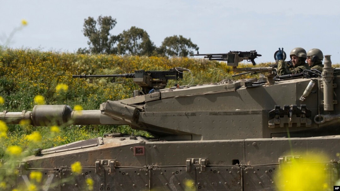 Israeli soldiers move on the top of a tank near the Israeli-Gaza border, as seen from southern Israel, March 21, 2024.